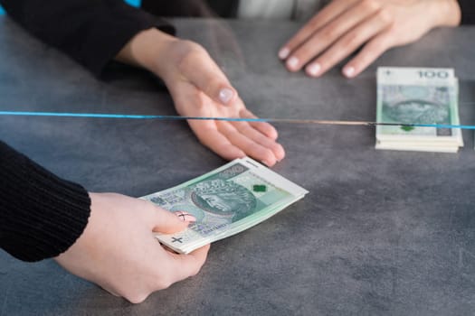 At a bank position, an employee accepts large sums of money from a young woman.