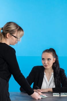 At a bank position, an employee accepts large sums of money from a young woman.
