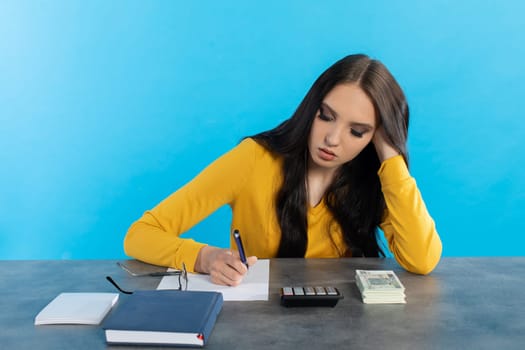 While counting money, a young woman uses a calculator and a tablet to check the stock exchange.