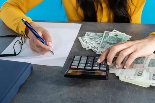On the desk lies a calculator, tablet and a stack of paper banknotes, which the young woman counts.