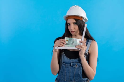 A woman in a hard hat holds a bundle of banknotes in her hand and encourages cooperation.
