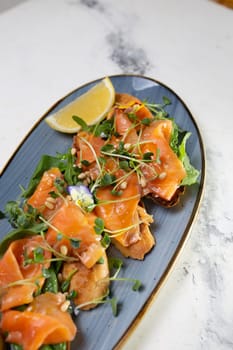 Delicious smoked salmon with lemon and microgreens served on a blue plate. Perfect for a healthy lunch or appetizer.