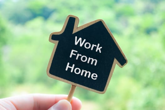 Work from home text on wooden house with nature background.