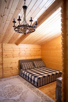 The bedroom is decorated with warm wood paneling and a soft, inviting bed. A beautiful chandelier provides soft lighting.