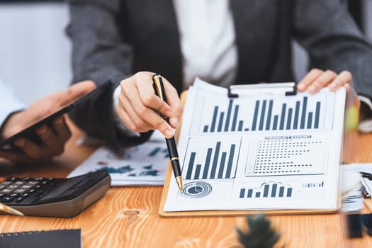 Multiracial analyst team use BI dashboard data to analyze financial report on meeting table. Group of diverse business people utilize data analysis by FIntech for business marketing decision. Concord