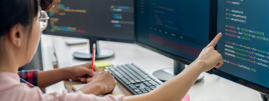 Female programer taking a note while young skilled web developer present program while computer displayed program code at modern office company. Java script, web design concept. Burgeoning.