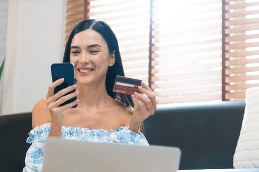 Young woman using online payment app and digital wallet on smartphone to pay with credit card. E commerce shopping and modern purchasing via mobile internet. Blithe