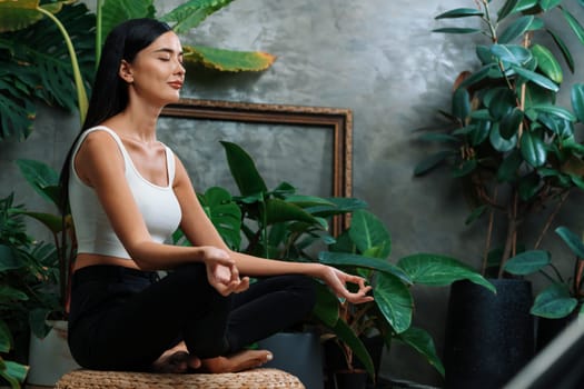 Young woman doing morning yoga and meditation in natural garden with plant leaf, enjoying the solitude and practicing meditative poses. Mindfulness activity and healthy mind lifestyle. Blithe