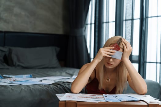 Stress worried young woman sit at table, as she pay bills online with credit card from financial debt problem, monthly expense and credit card debt. Over spending money lifestyle problem. Blithe