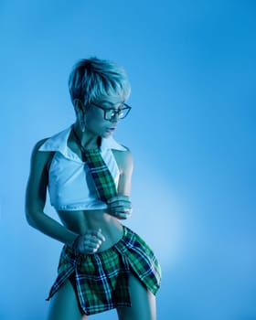 Sexy girl in an erotic school plaid skirt costume from a sex shop in blue neon light on copy paste background