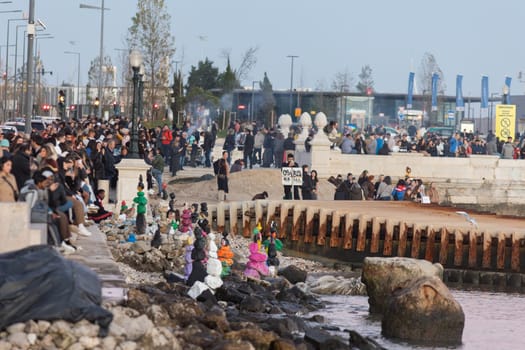 17 december 2023, Lisbon. Portugal - Commerce plaza - a large crowd of people are gathered on a beach, with some holding signs and others sitting on the rocks. Scene is one of excitement and anticipation