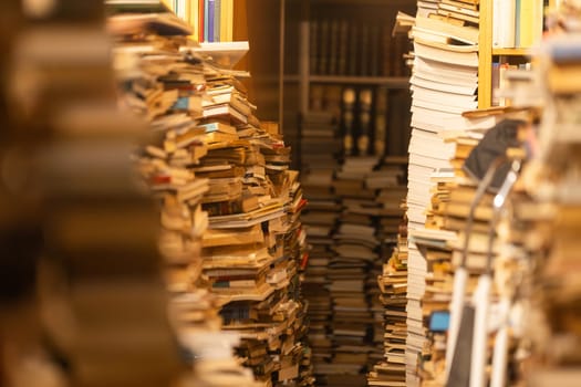 A bookcase filled with books is shown in a close up. The books are piled high and the shelves are overflowing. Concept of chaos and disorganization, as the books are not neatly arranged