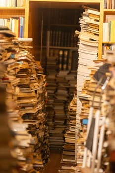 A bookcase filled with books is shown in a close up. The books are piled high and the shelves are overflowing. Concept of chaos and disorganization, as the books are not neatly arranged