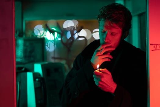 A man is smoking a cigarette in a telephone booth. The room is filled with a red and green glow, giving it a mysterious and eerie atmosphere. The man's face is obscured by the smoke
