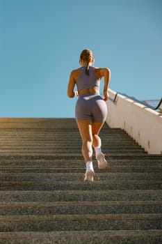 Athletic woman in sportswear is jogging around the city in early morning. Reaching the goal