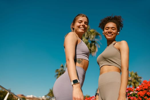 Smiling female sportswomen have a rest after morning jogging outdoors and looks camera