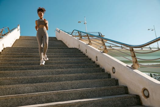 Athletic woman in sportswear is jogging around the city in early morning. Reaching the goal