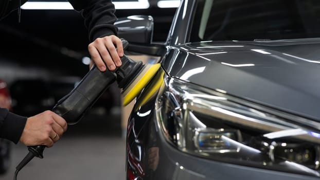 A master polishes the surface of a car body