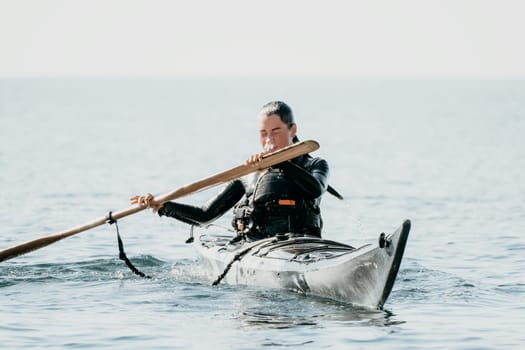 Happy smiling woman in kayak on ocean, paddling with wooden oar. Calm sea water and horizon in background