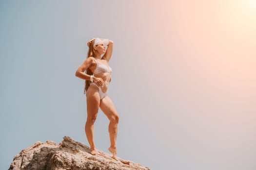 Woman meditating in yoga pose silhouette at the ocean, beach and rock mountains. Motivation and inspirational fit and exercising. Healthy lifestyle outdoors in nature, fitness concept.