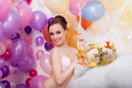 Image of smiling young woman posing with bunch of balloons