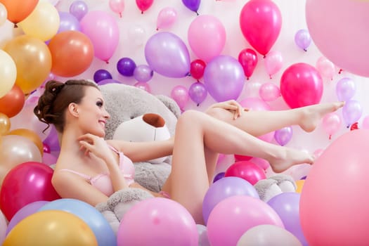 Pretty slim model posing with balloons and teddy bear