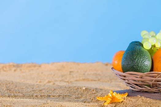 Blue sky over the sea beach. Ripe southern fruits lie in the basket. Sea shore of a sandy beach.