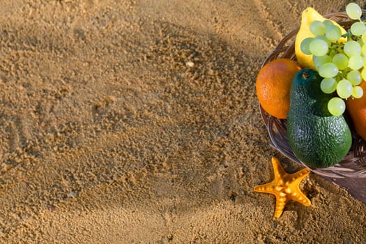 Ripe southern fruits lie in the basket. Sea shore of a sandy beach.