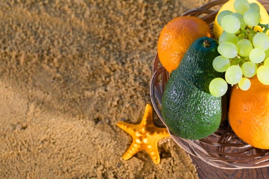 Ripe southern fruits lie in the basket. Sea shore of a sandy beach.