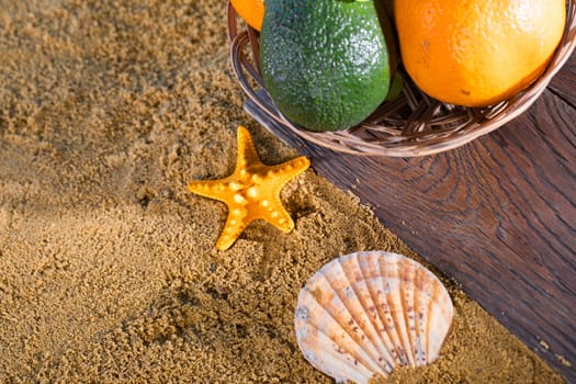 Ripe southern fruits lie in the basket. Sea shore of a sandy beach.