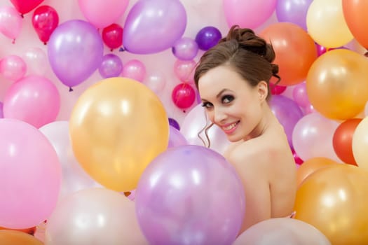 Image of smiling young woman posing with balloons