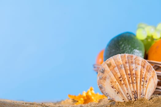 Blue sky over the sea beach. Ripe southern fruits lie in the basket. Sea shore of a sandy beach.