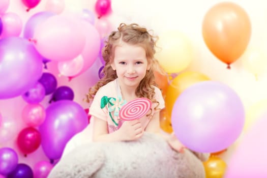 Adorable curly girl posing on balloons background