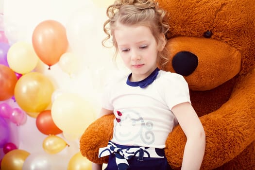 Image of cute girl posing in embrace with big teddy bear