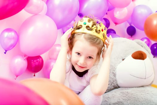 Portrait of funny little girl trying on crown in studio