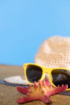 Blue sky over the sea beach. A summer hat and sunglasses lie on the sandy coast of the sea beach.
