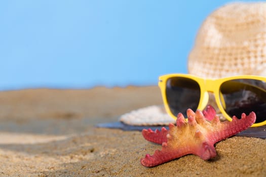 Blue sky over the sea beach. A summer hat and sunglasses lie on the sandy coast of the sea beach.