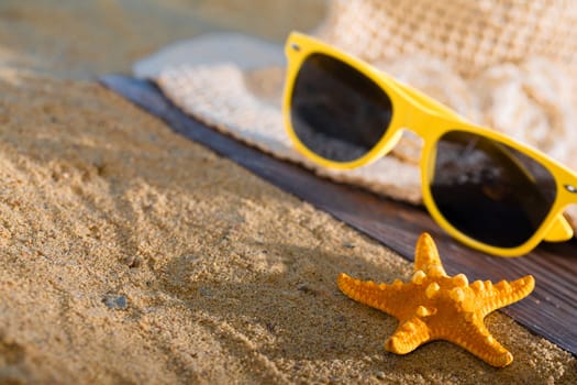 A summer hat and sunglasses lie on the sandy coast of the sea beach.