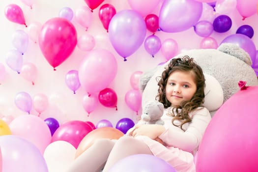 Playful little girl posing in studio with colorful balloons