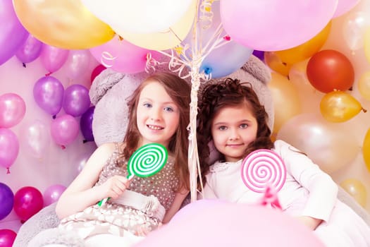 Beautiful little sisters with lollipops posing at camera