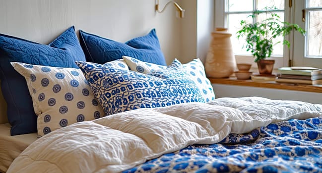 Bed with blue and beige pillows and bedspreads. Interior design of a modern bedroom in a country house.