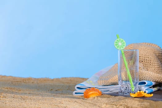 Summer hat for a holiday. An empty glass for a refreshing drink. A patch of blue sky.