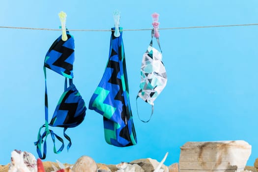 Women's swimsuit hangs on a string. Sea beach with wet sand.