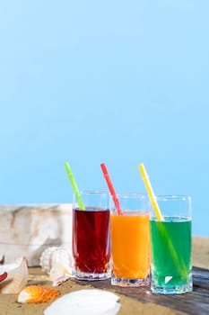 Fresh fruit juice in a tall glass. Shore of a sandy beach on a cool sea.