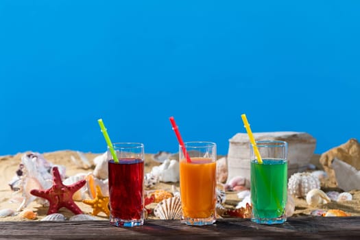 Fresh fruit juice in a tall glass. Shore of a sandy beach on a cool sea.