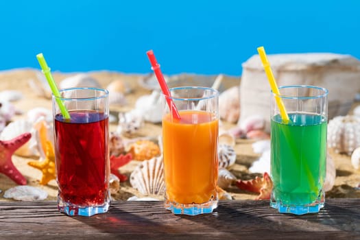 Fresh fruit juice in a tall glass. Shore of a sandy beach on a cool sea.