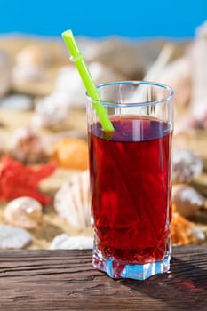 Fresh strawberry juice. A sandy beach on the shores of a cool sea. Brown platform board.