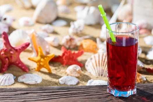 Fresh strawberry juice. A sandy beach on the shores of a cool sea. Brown platform board.