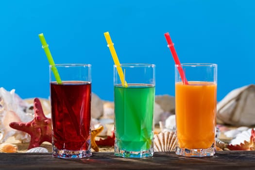 Fresh fruit juice in a tall glass. Shore of a sandy beach on a cool sea.