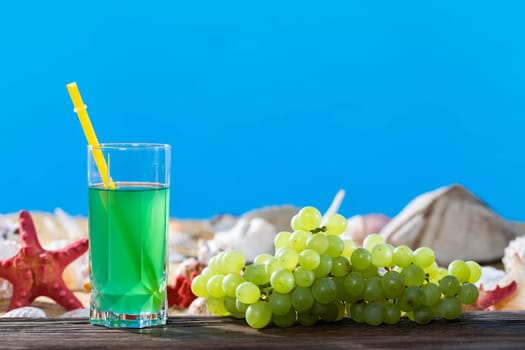 Bunch of grapes. Fresh grape juice. A sandy beach on the shores of a cool sea. Brown platform board.